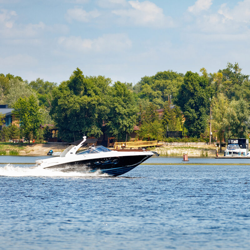 The motor boat moves quickly along the water surface of the river.